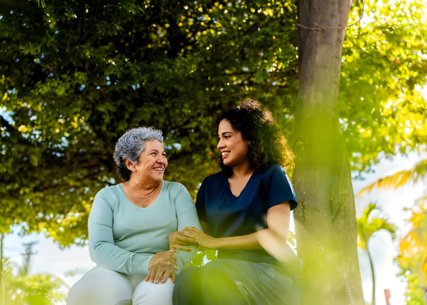 An older woman and caregiver enjoying a conversation outdoors